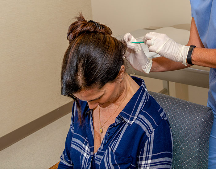 patient receiving Botox® injections at the back of her head for migraine treatment